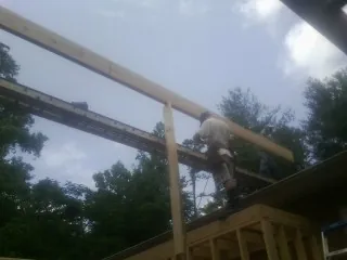 Carpenter setting a ridge beam over a new addition frame — Ice Dam Removal by Roofing Brothers in Hardy