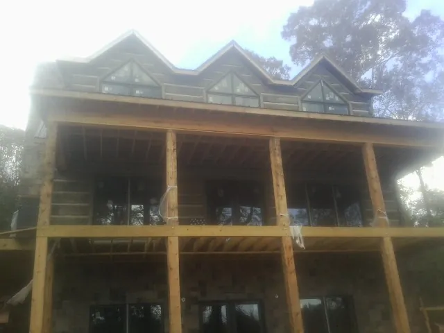 Dormers and porch framing on a large log home under construction — Roof Coating work by our crew in Hardy