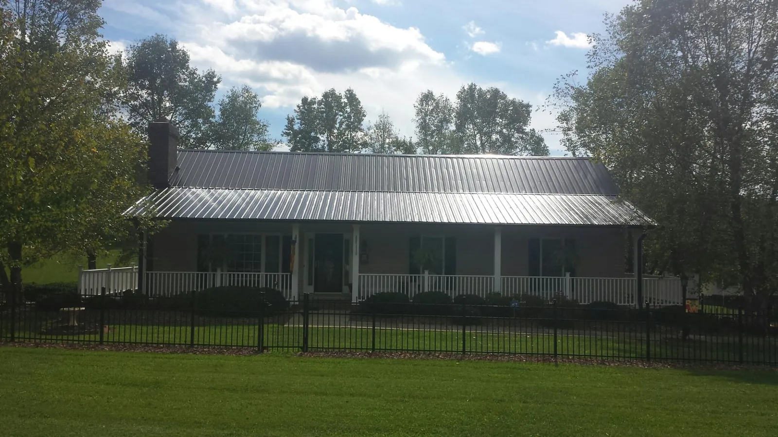 Gray metal roof on a brick ranch with a full width front porch — Gutter Guard Installation work by our crew in Hardy